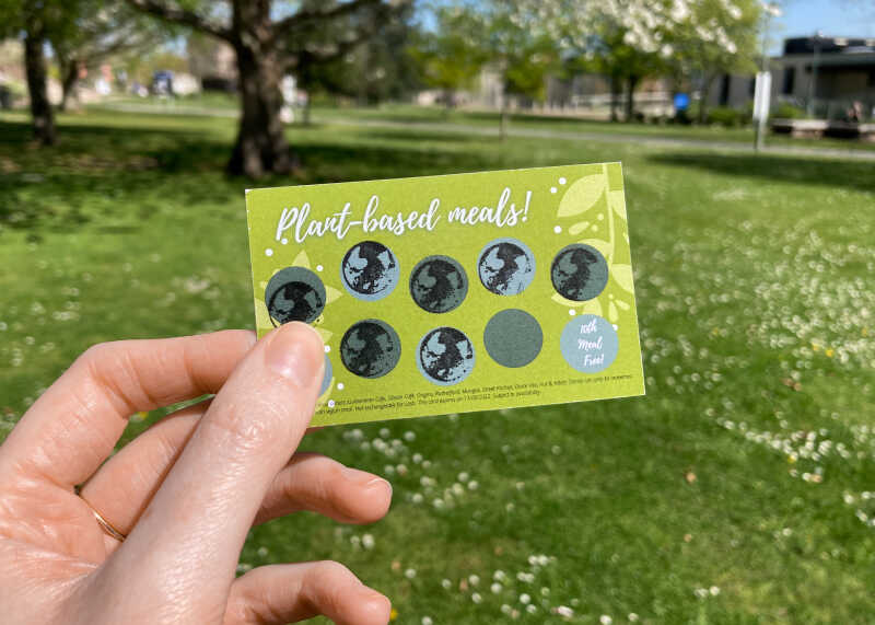 A hand holding a plant-based loyalty card that has been stamped 8 times