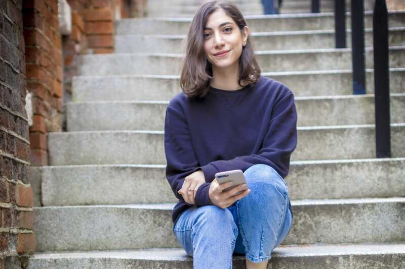 Person sitting on steps holding mobile phone