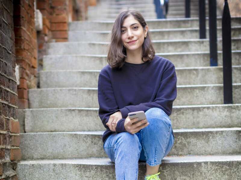 Person sitting on steps holding mobile phone.