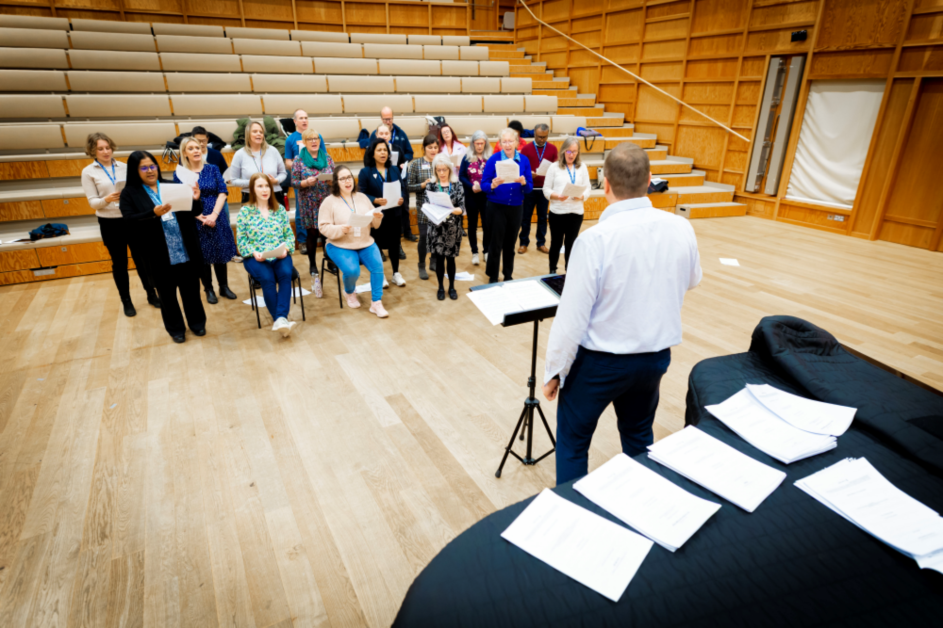 Group of singers in rehearsal, conductor and piano in the foreground