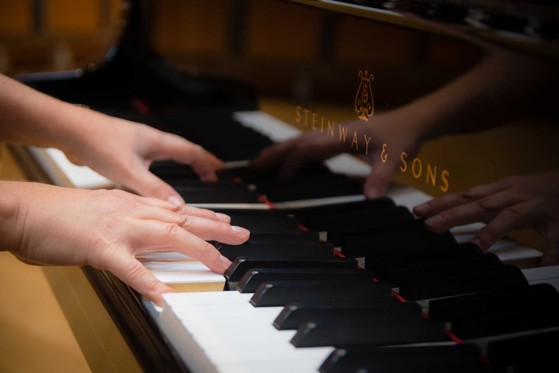 Close up of a pair of hands at a grand piano keyboard