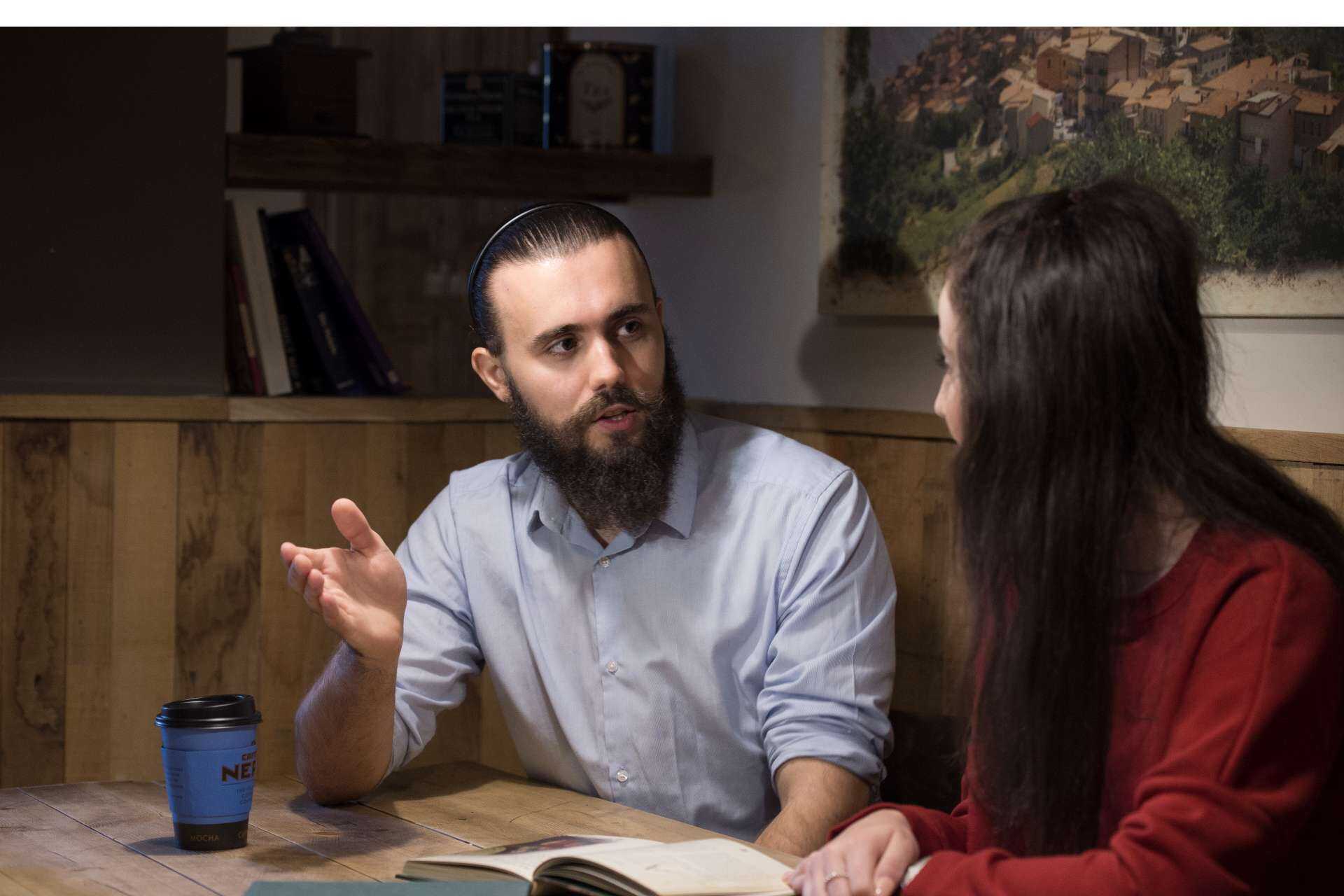 Male and female University of Kent students in conversation, seated in a coffee shop