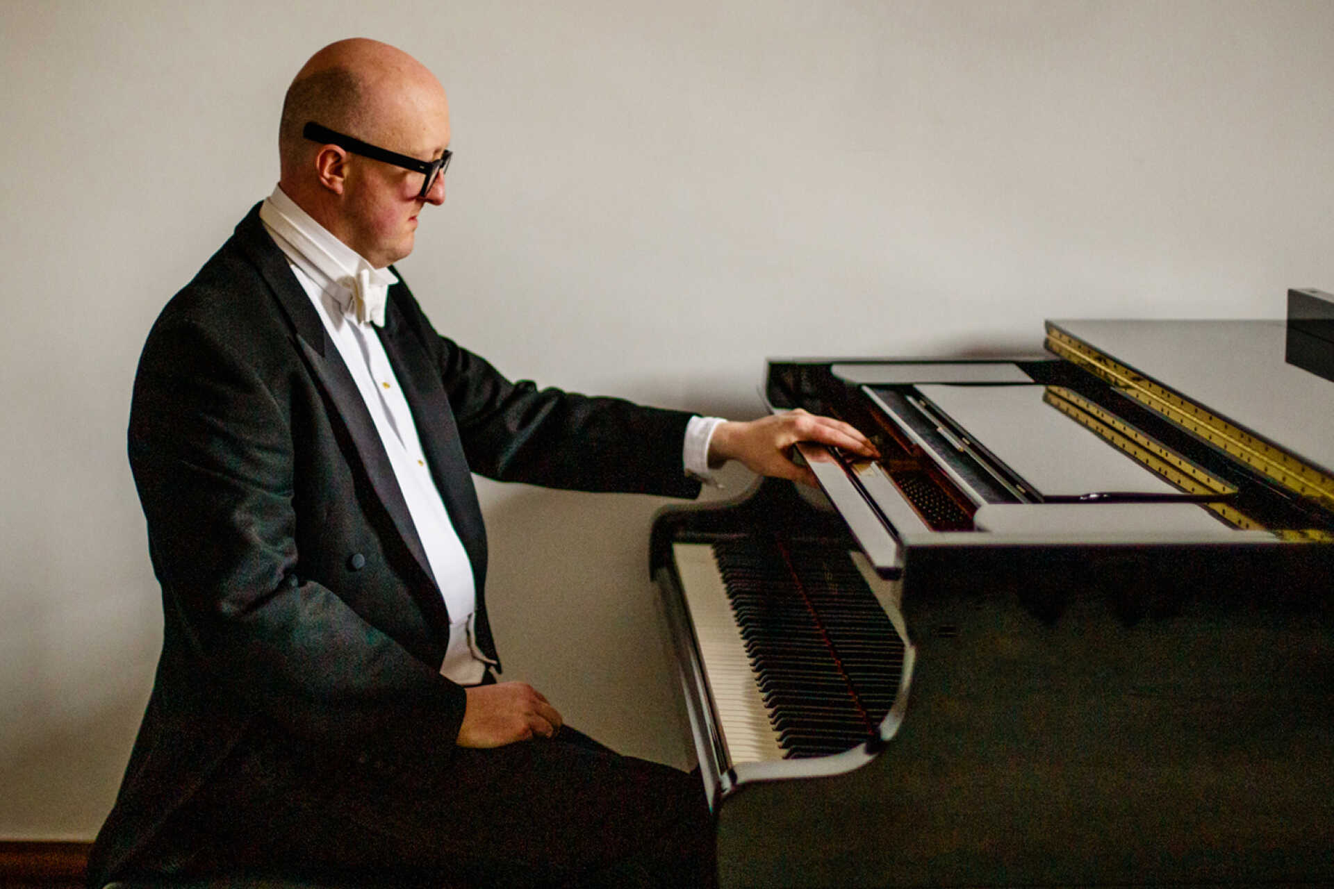 Formal image of dinner-jacket wearing pianist sat at a grand piano
