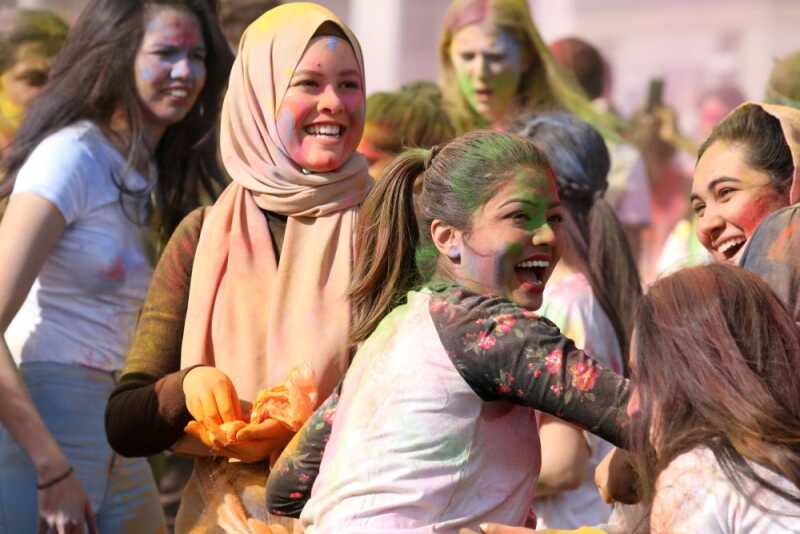 Students celebrating at Holi with colourful paint