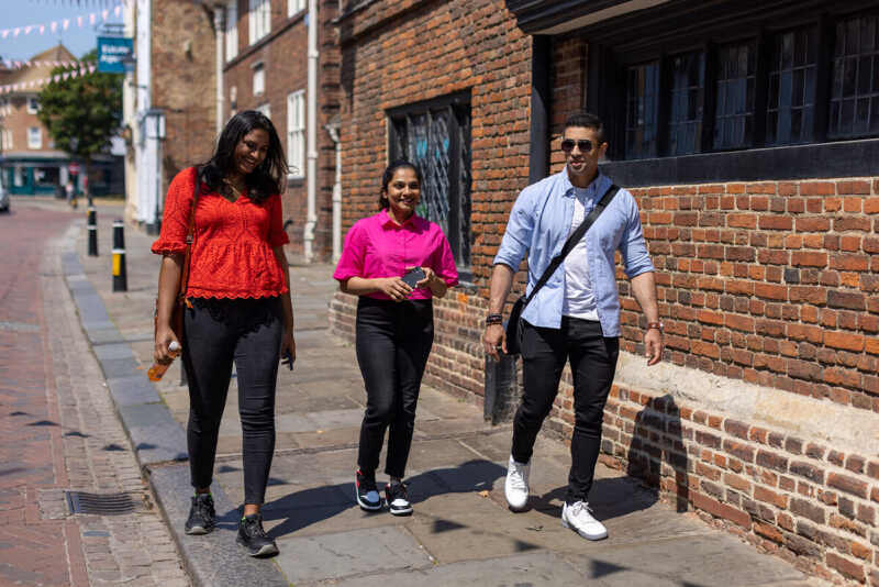 Three students walking along Rochester highstreet.