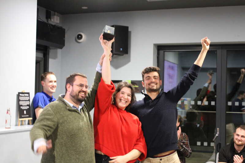 Three team members hold up a small trophy after winning the VC's Cup The Cube competition