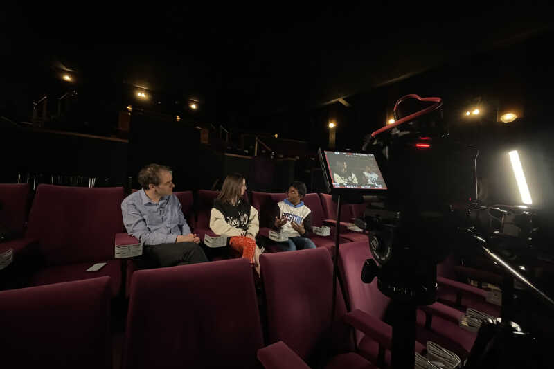 Three people being filmed in a small cinema
