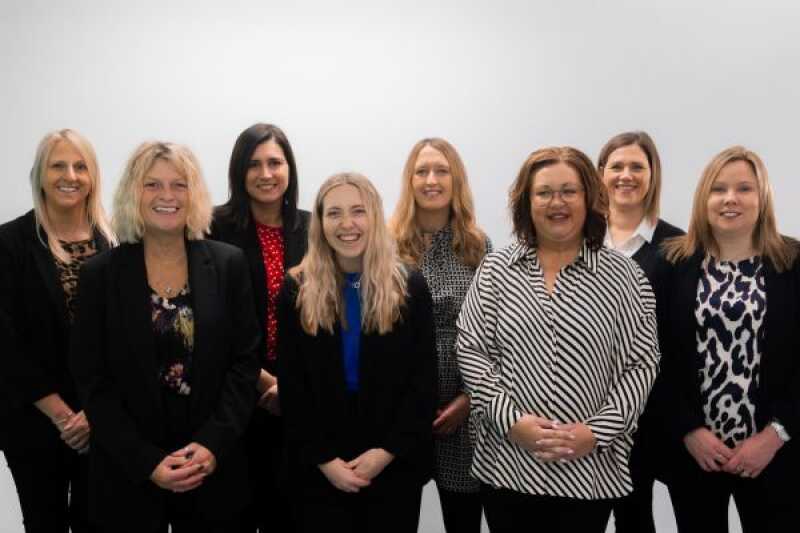 8 members of the conferences and events team, standing side by side, smiling for the camera.