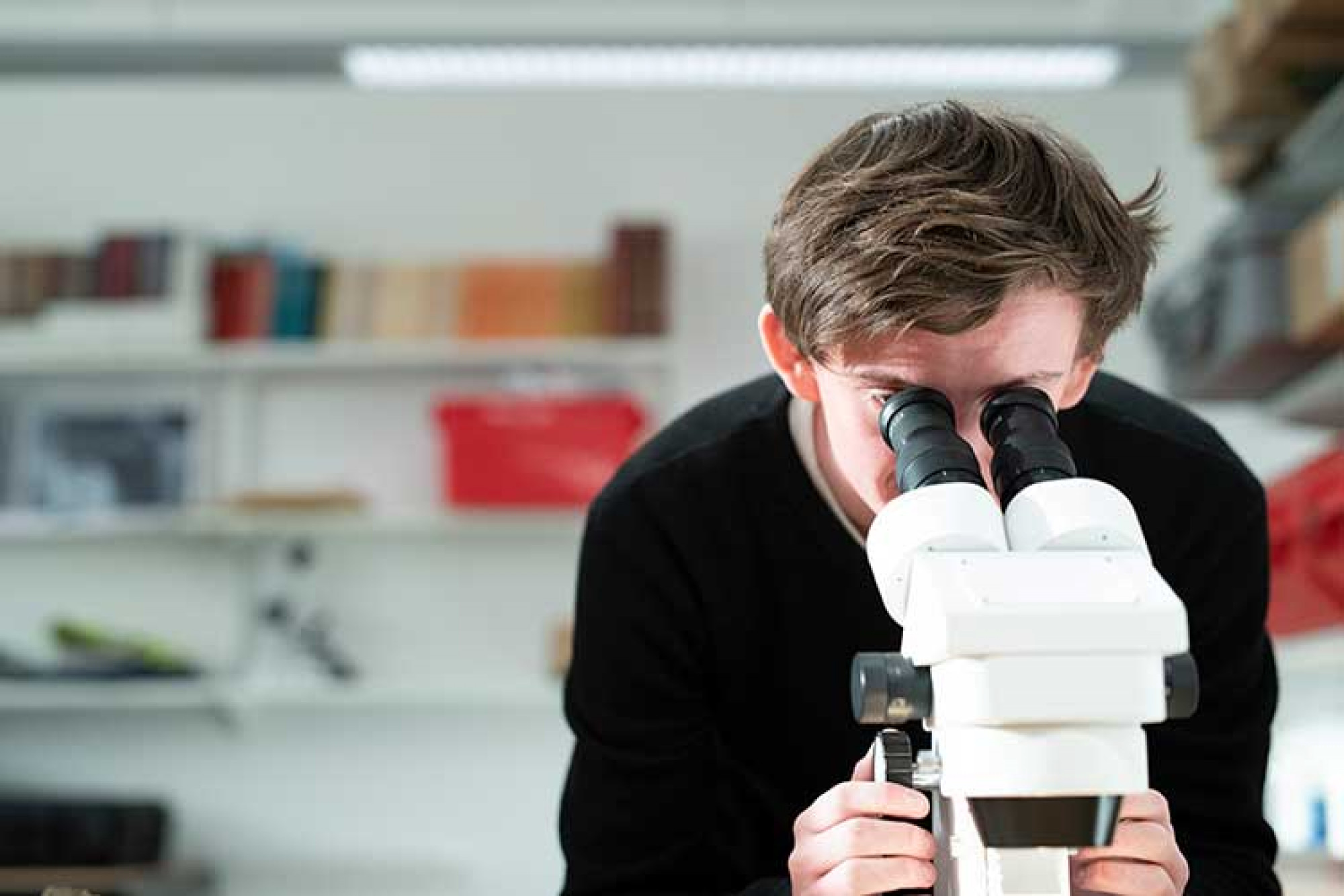 Male student looking into microscope