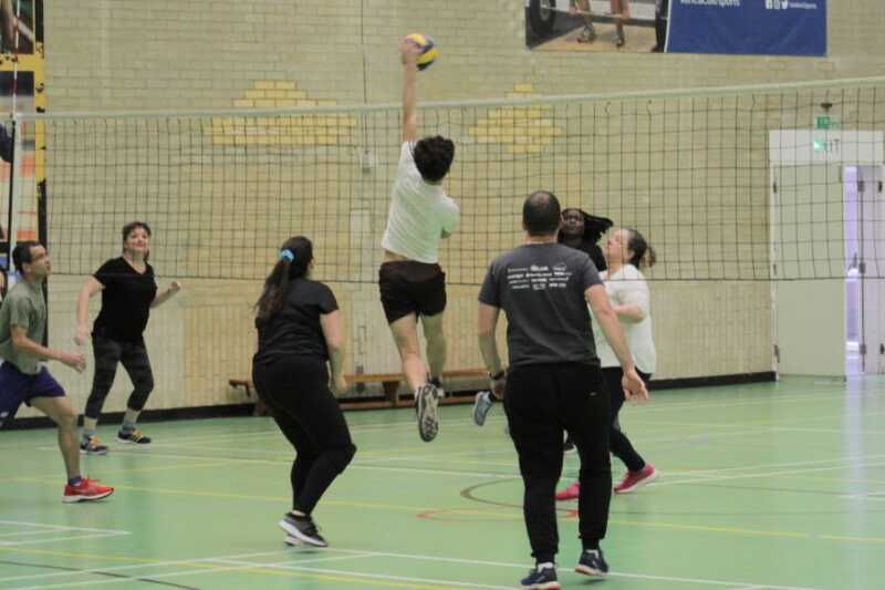 Volleyball player jumping up at the net to deflect the ball.