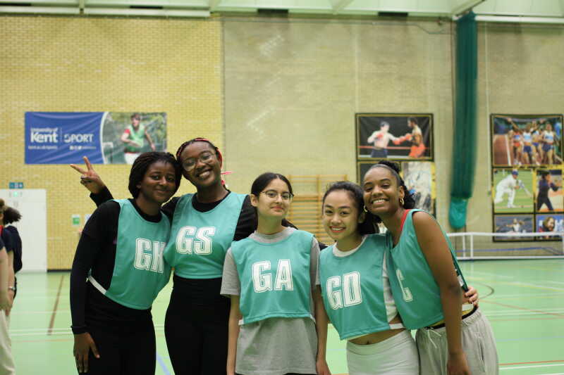 Five students in netball bibs pose for the camera during our ResLife Sports Cup competition