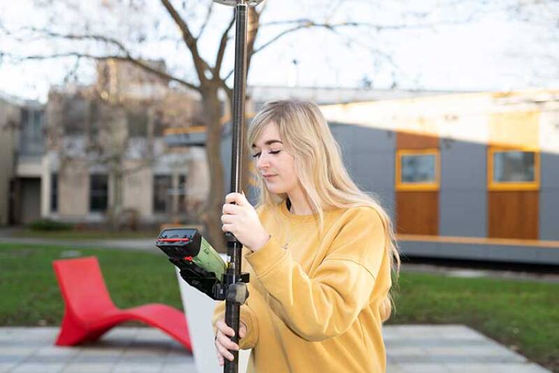 Student long blonde hair, yellow sweatshirt using GPS equipment