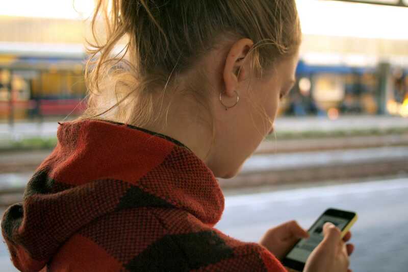 A woman plays on her phone at a train station
