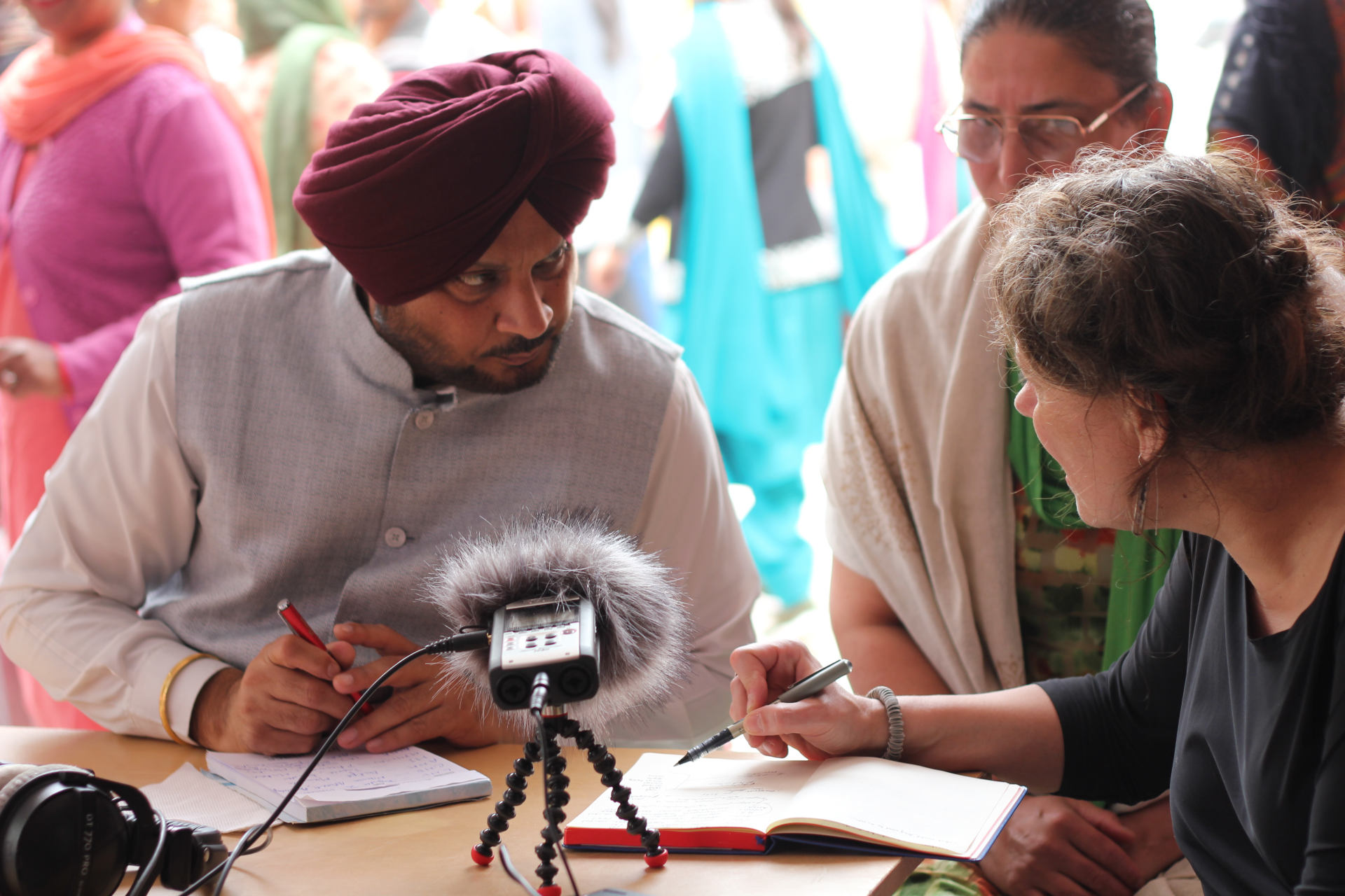 A man in a turban speaks to a female researcher during a podcast recording