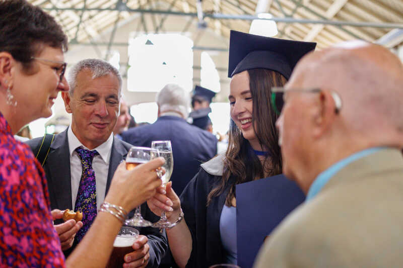 Graduate and guests clinking glasses in celebration