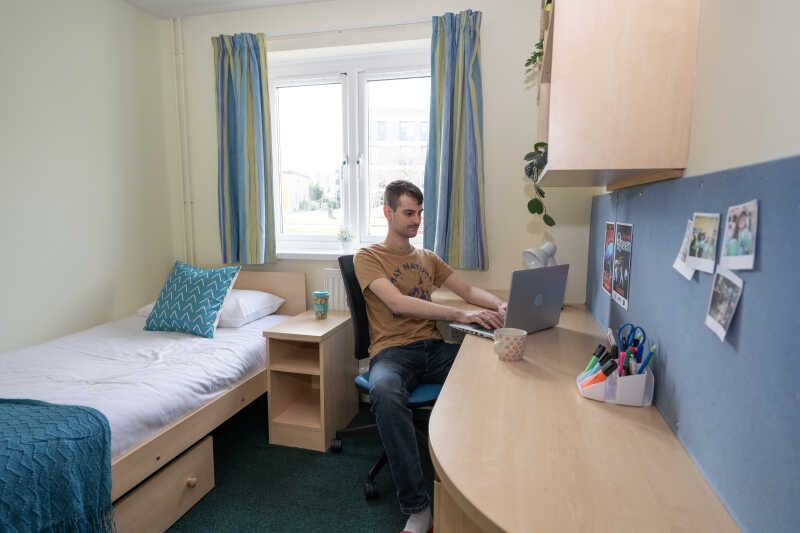 Male student working at desk in Darwin House bedroom