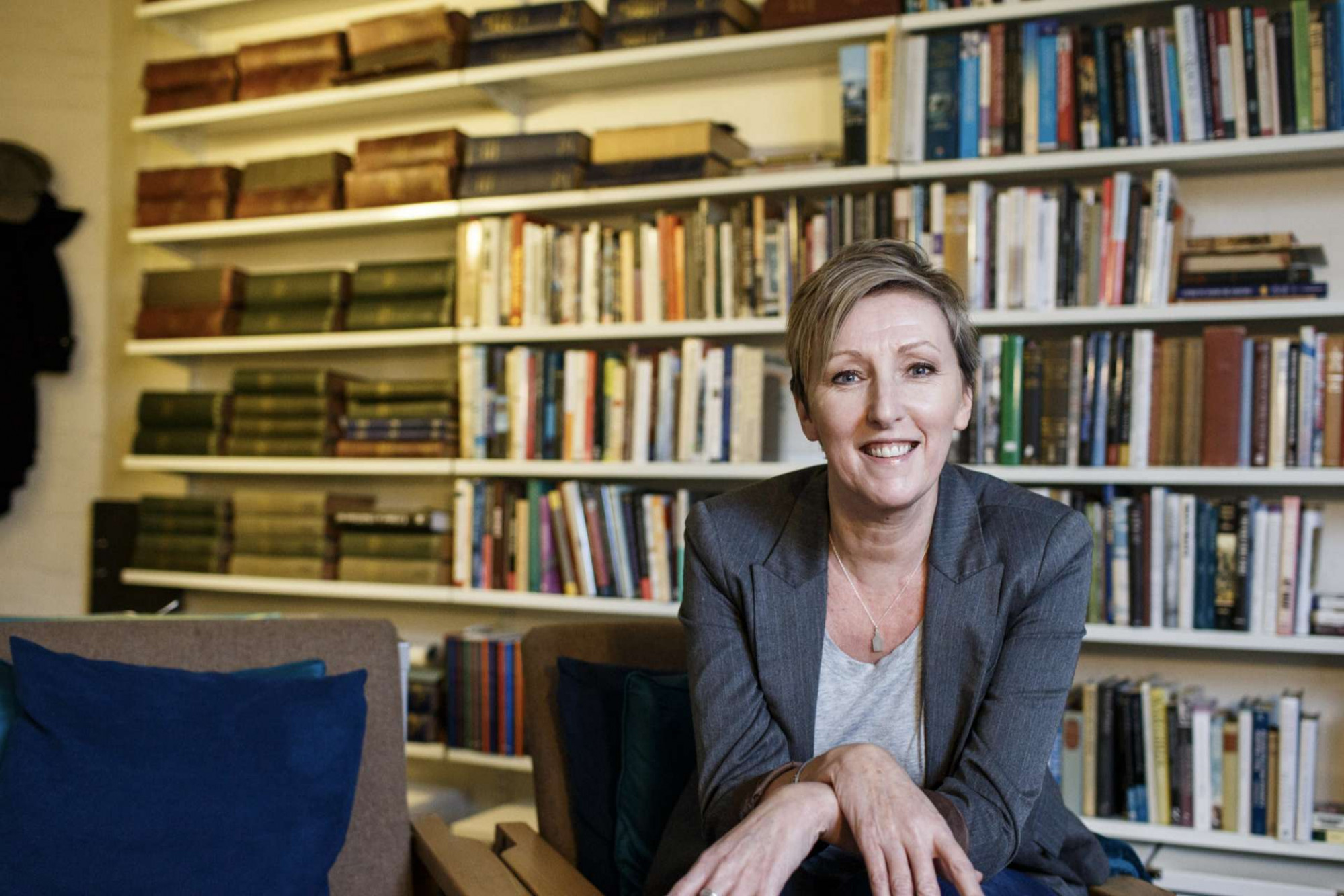 Dr Julie Anderson sits in front of bookshelves.
