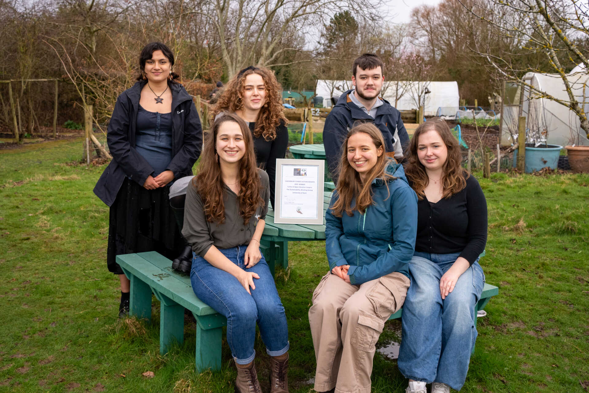 The Sustainability Working Group sitting smiling on a bench with their award
