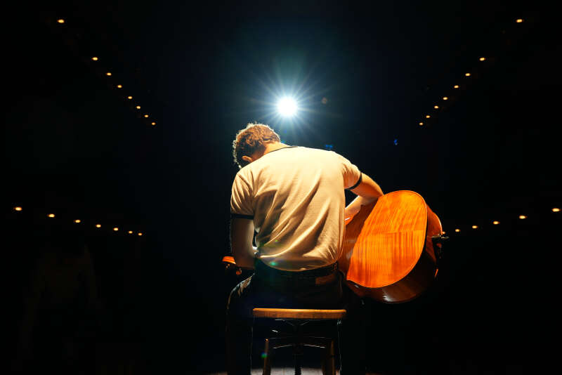 Male cellist on-stage photographed from the back