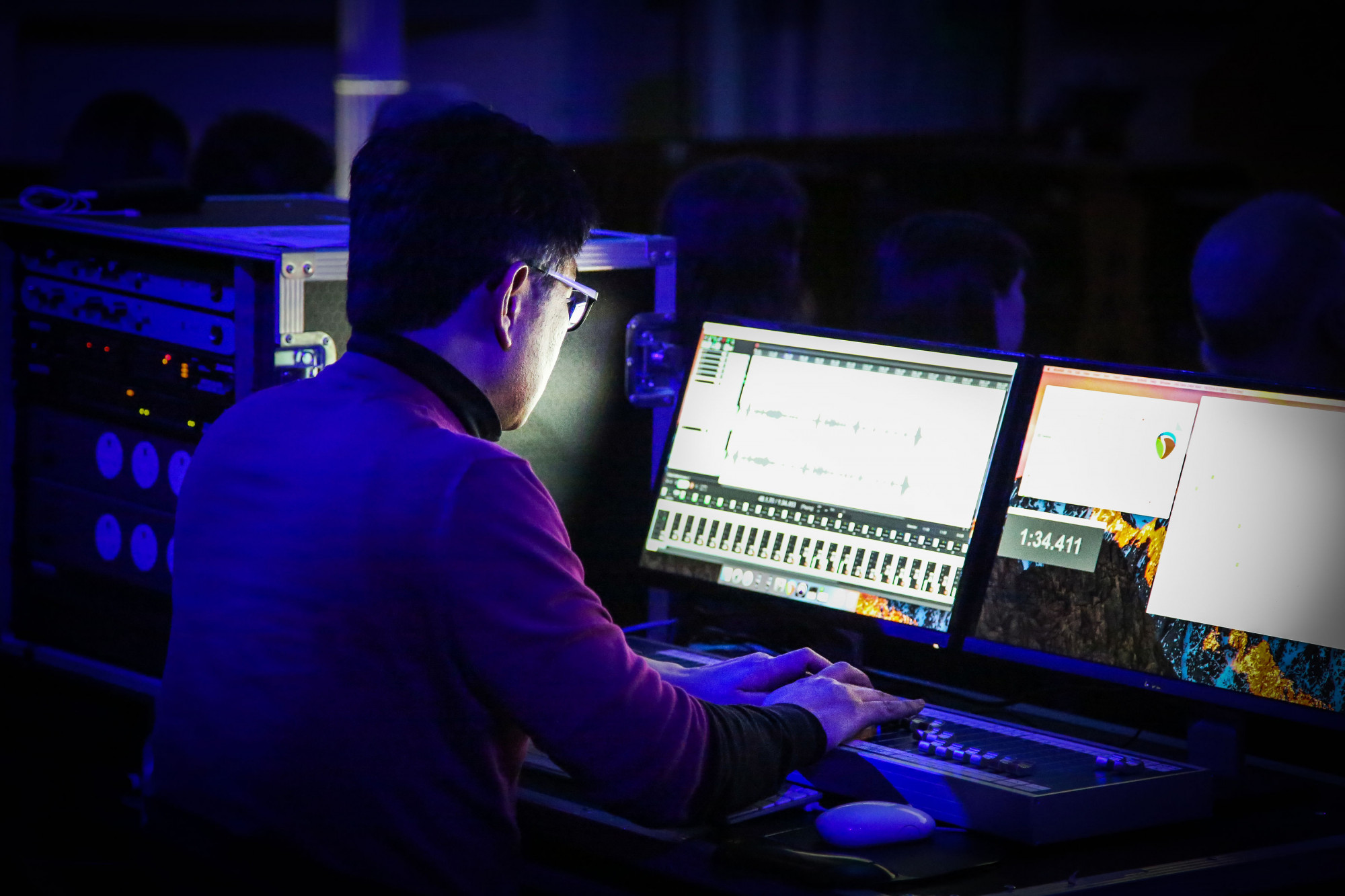 Student looking at two screens in the Music and Audio Arts Sound Theatre.