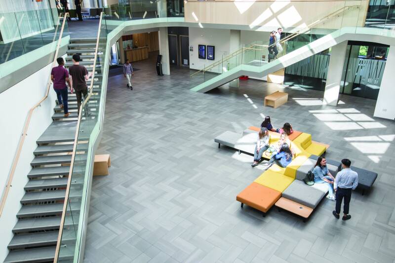 Foyer of Sibson building, students sitting in centre and two staircases