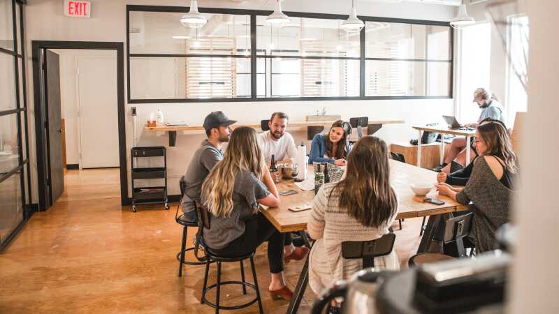 People in their late thirties and forties sitting in an office around a table discussing