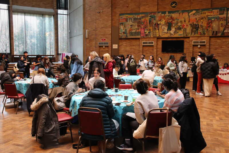 Group of students sitting round a table painting baubles