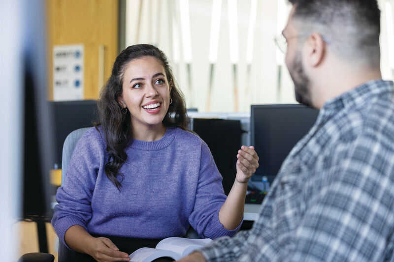 People in their late thirties and forties sitting in an office around a table discussing