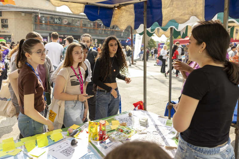Image shows a group of students visiting a stand on the Canterbury Campus