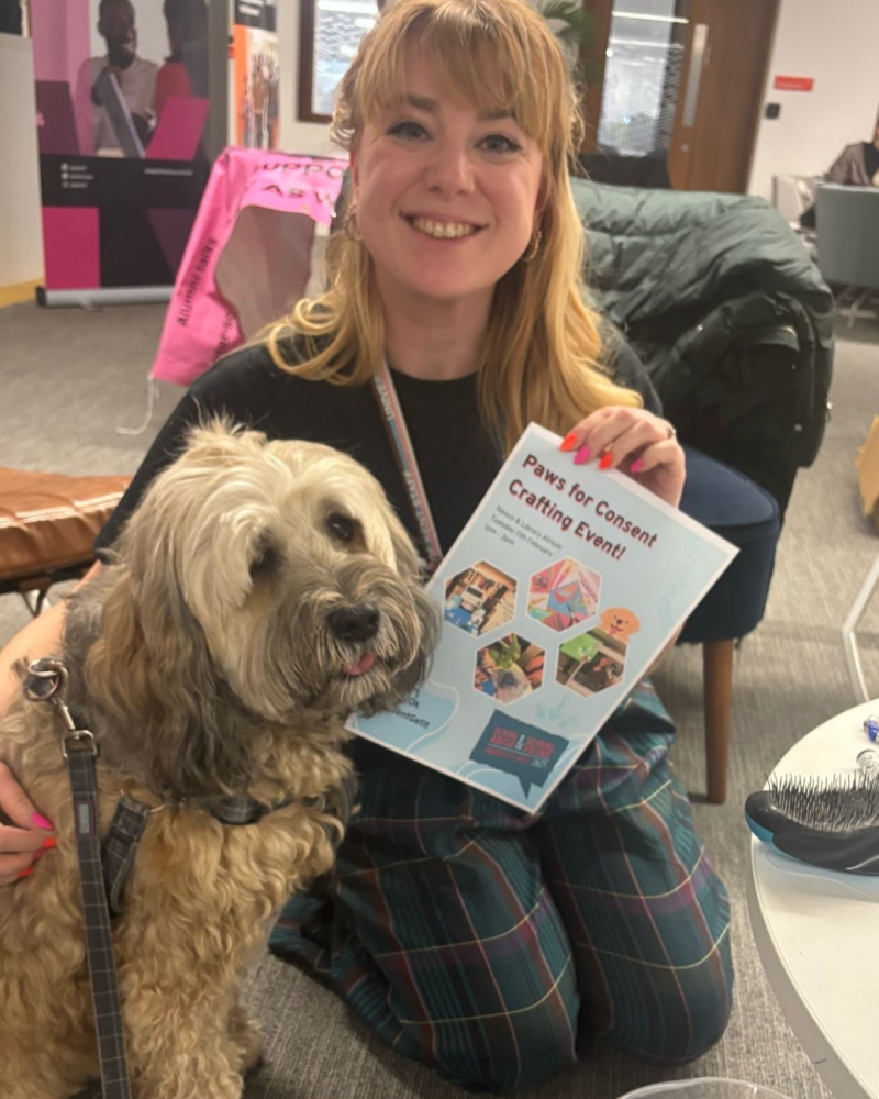 Staff member smiling with Coco the therapy dog at Paws for Consent crafting event