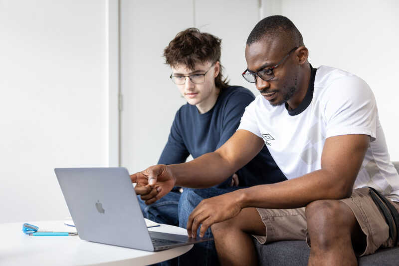 Student and staff member talking with laptops