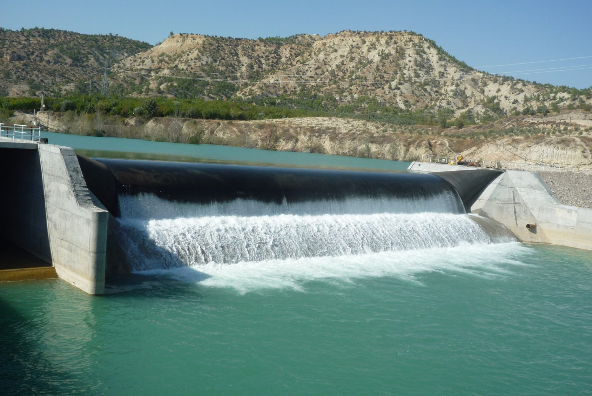 A dam with overflow being restricted through an inflatable mechanism