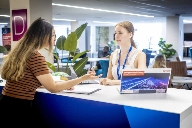 Image shows an IT support staff member talking to a woman