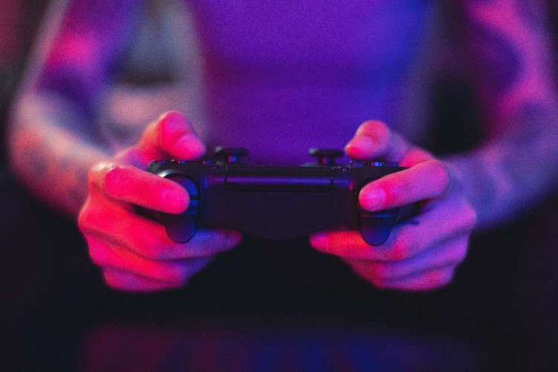 close up of hands on game controller, purple and pink lighting