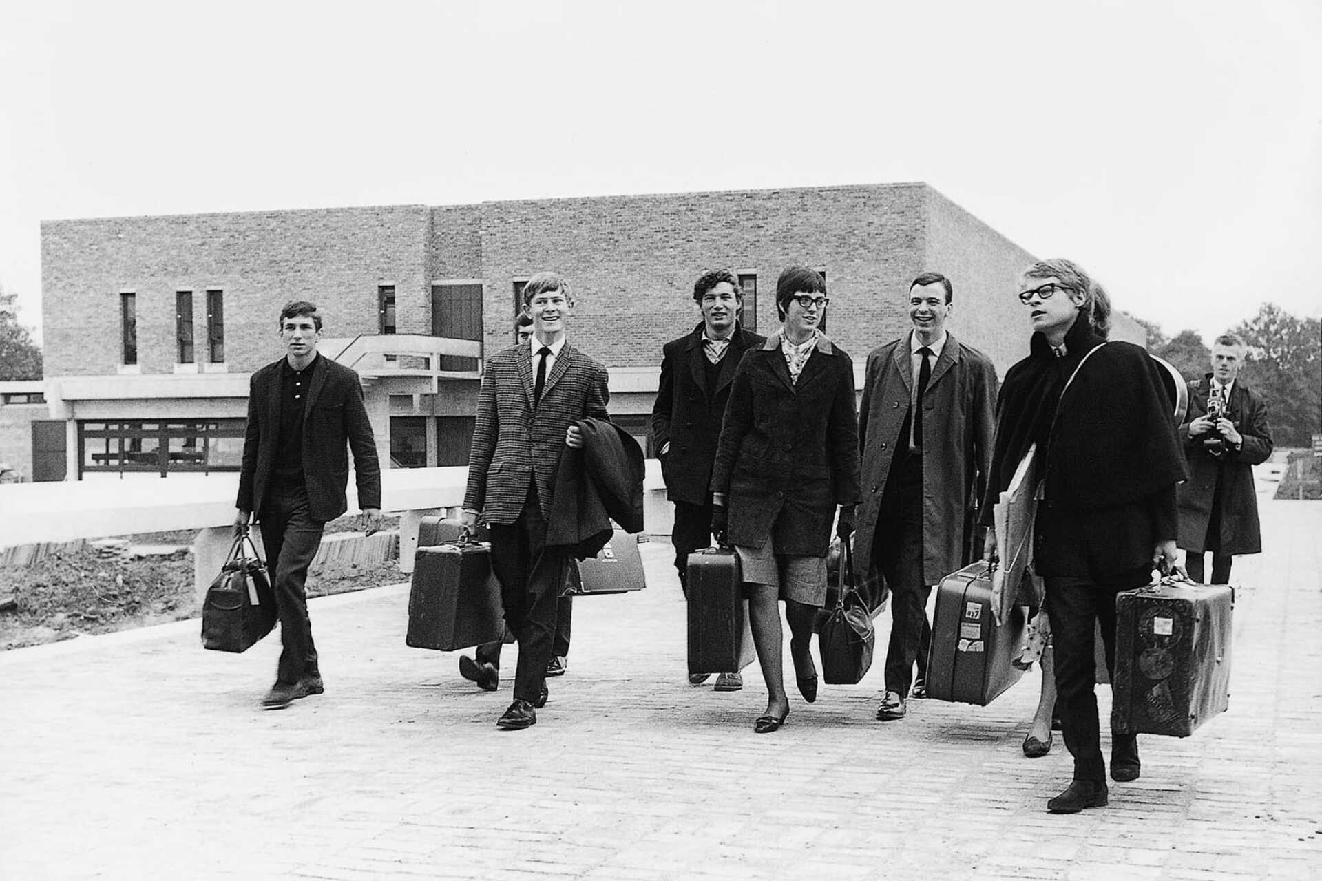 Black and white photo of first students carrying suitcases