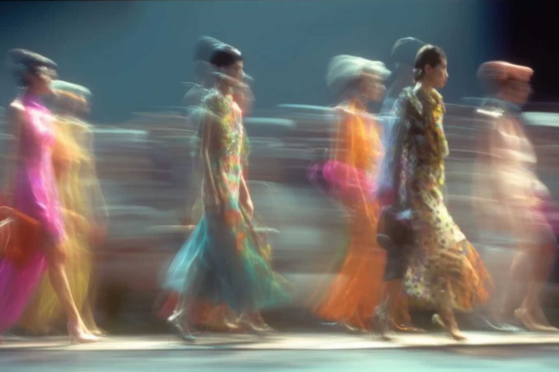 A female student in lab coat and goggles poses next to a fume hood