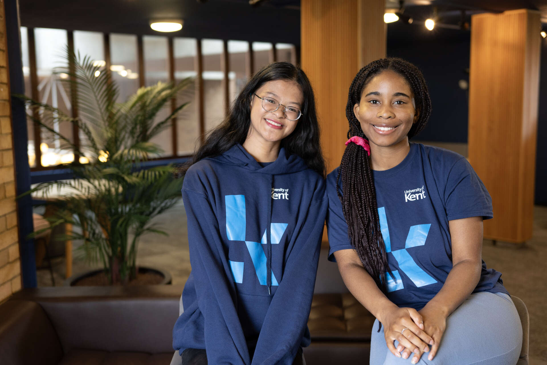 Group of university students in blue Kent shirts laughing together in a lounge area.