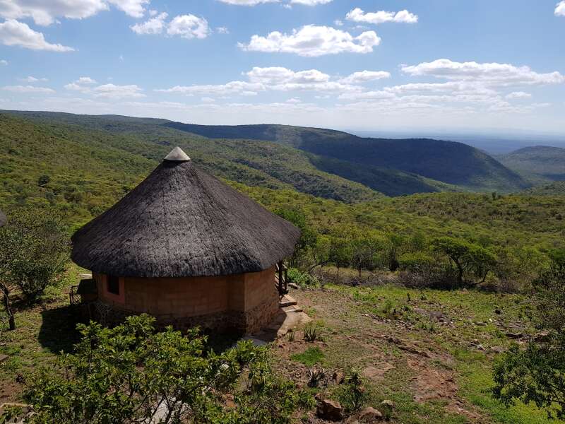 Vista across open scrub and rocky terrain with small thatched hut in corner