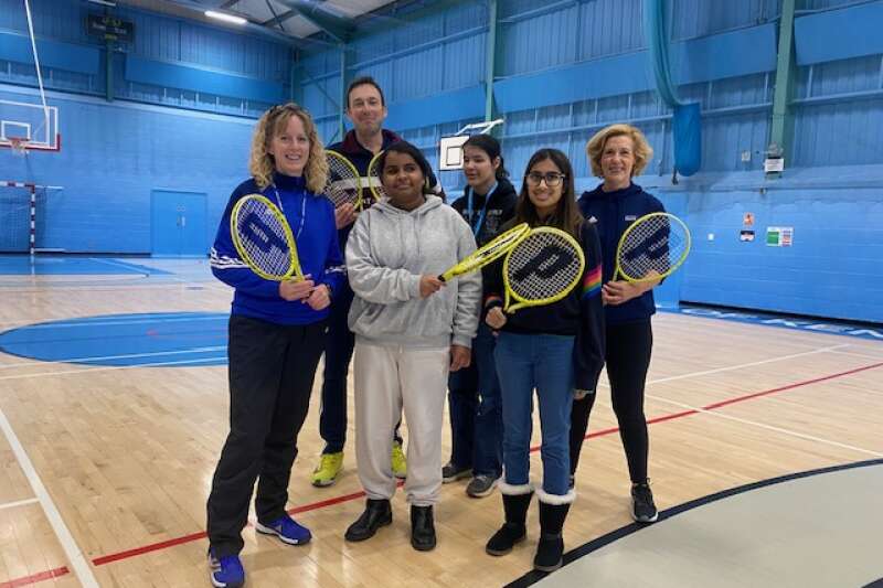 Group of people looking at the camera and smiling while holding tennis rackets