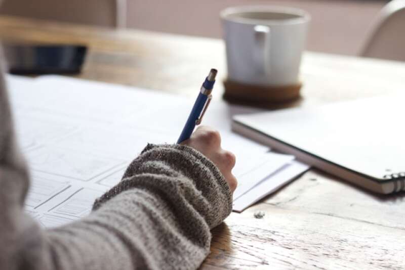 Person writing on brown wooden table