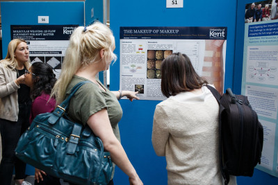 Two visitors look at an academic poster during the Postgraduate Researchers' Showcase