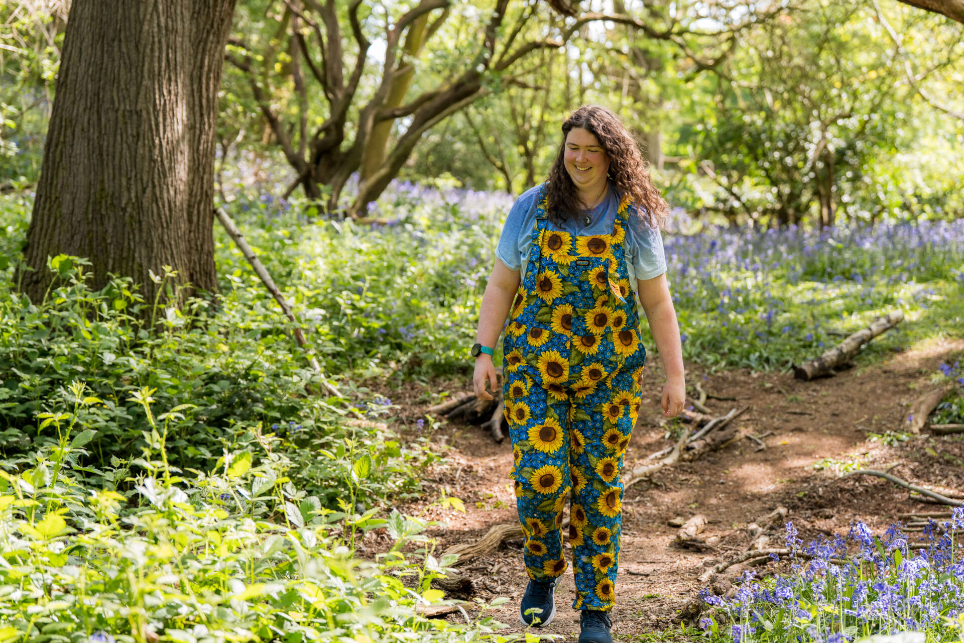 Elinor smiling and walking through bluebells on campus