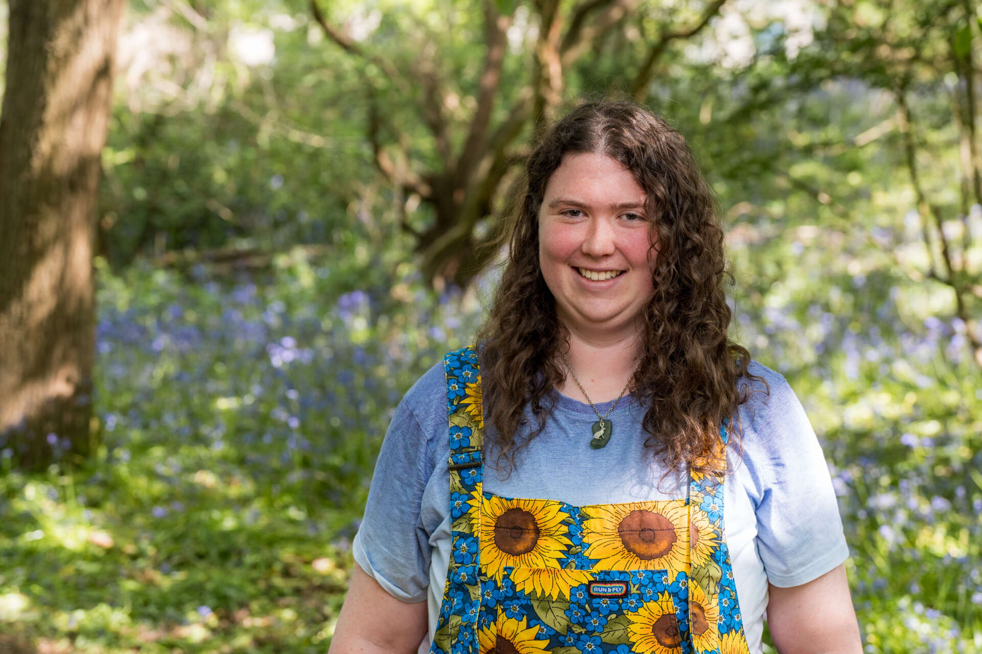 Student Elinor walking through bluebells smiling
