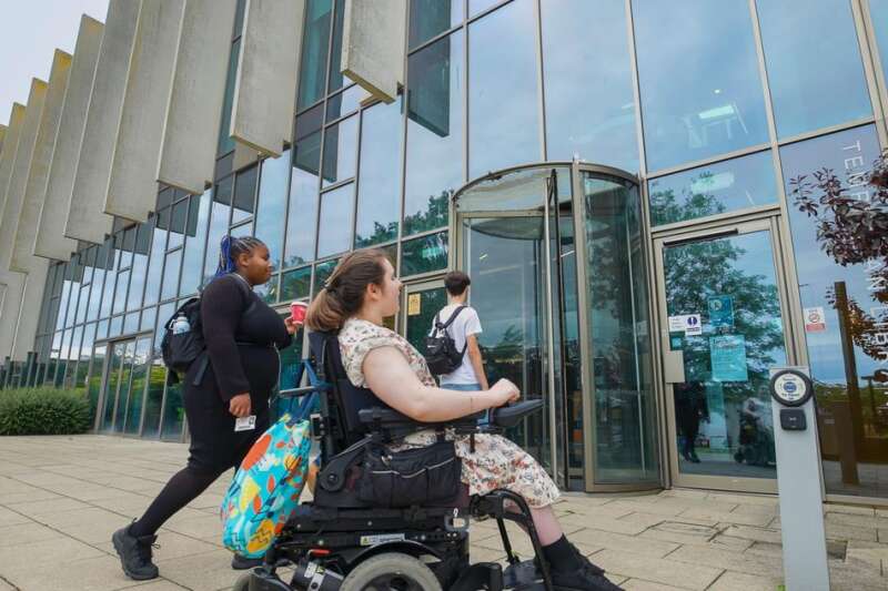 Student in wheelchair walking with other students into Templeman Library
