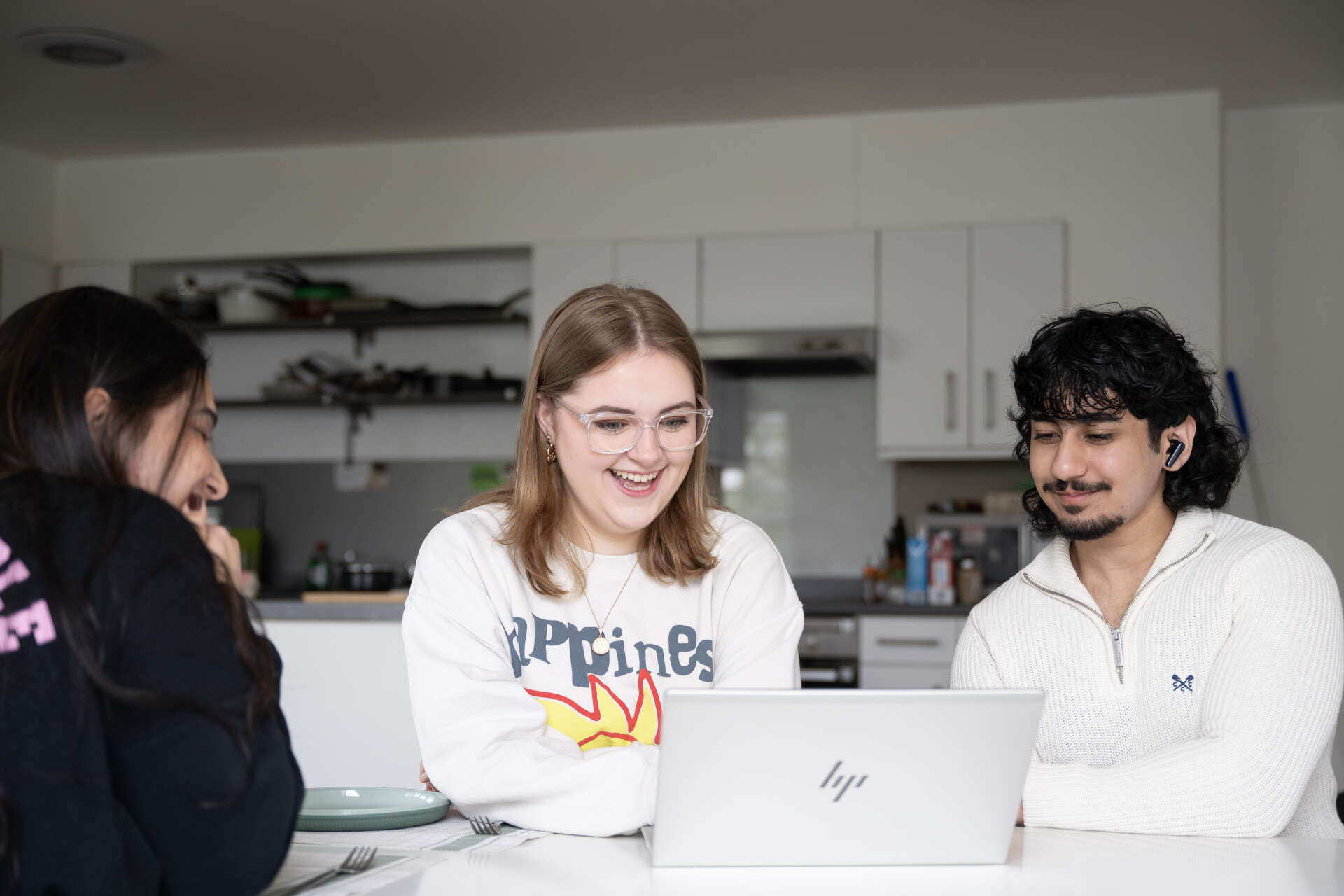 Three students looking at a laptop and laughing