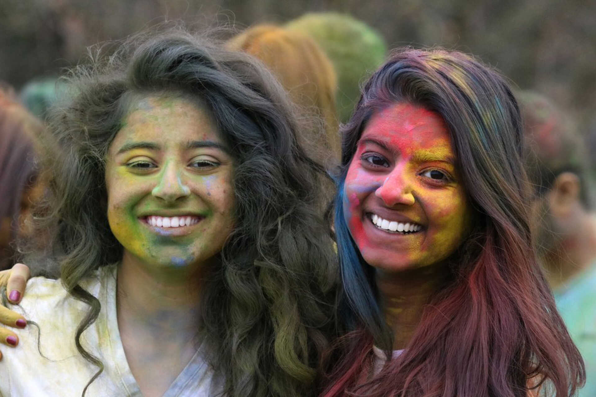 Two female students covered in paint celebrate the Holi Festival