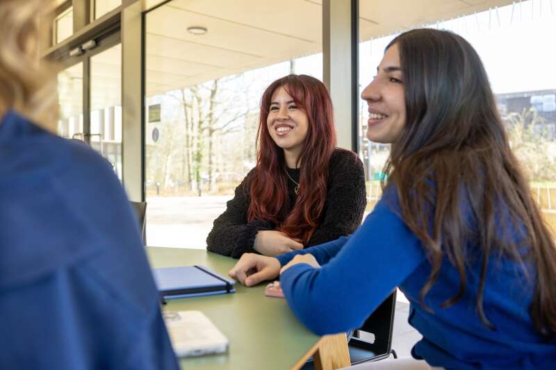 Group of students sat around a table having a discussion