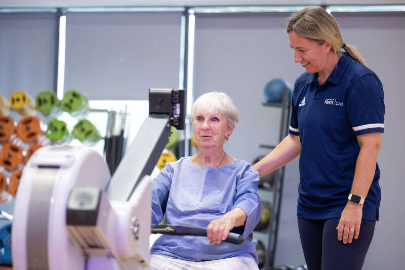 Cardiac rehabilitation client sitting on a rowing machine while a staff member is instructing them