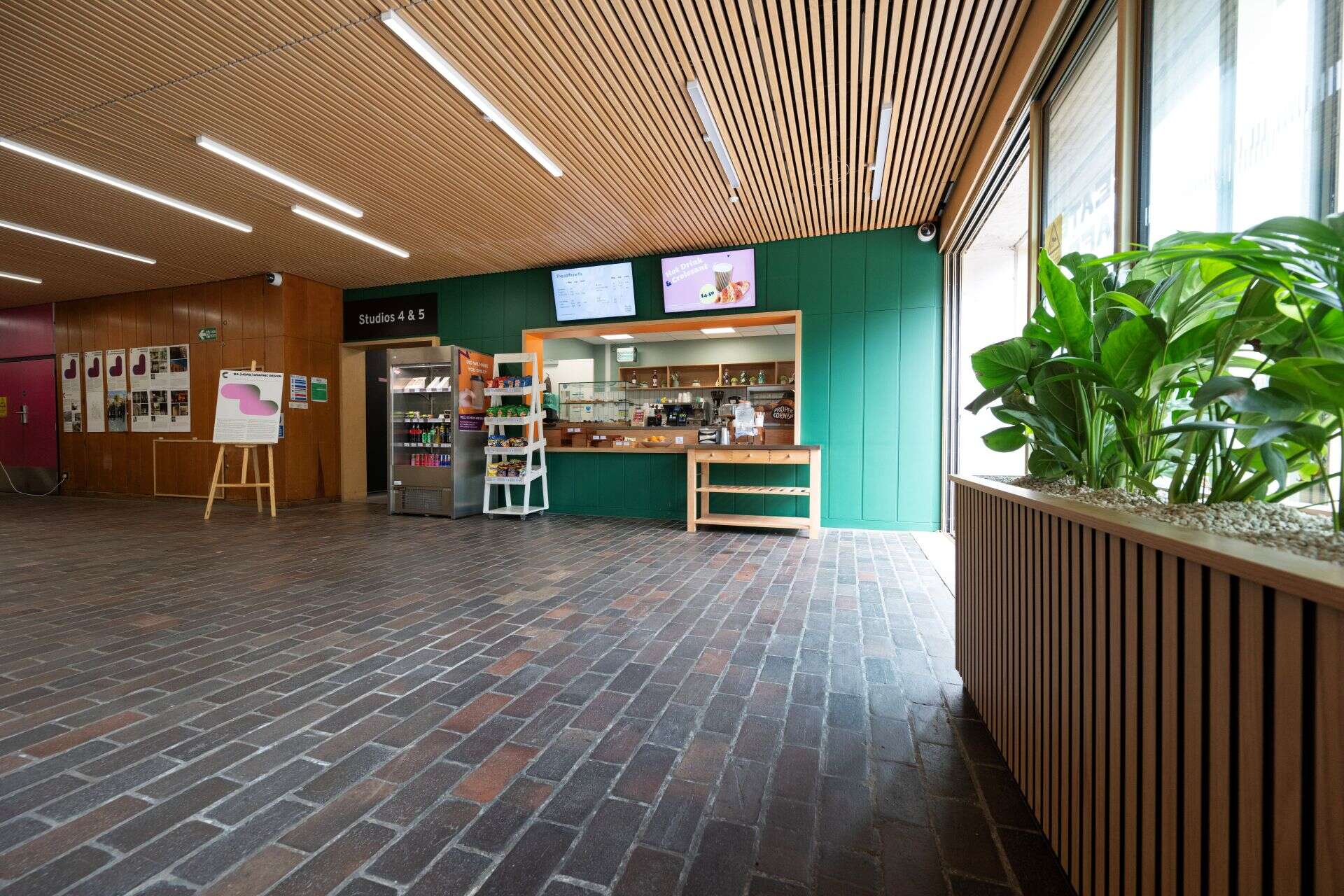 Two women chatting over coffee in a bright café, one with a laptop open, both smiling and enjoying their conversation.