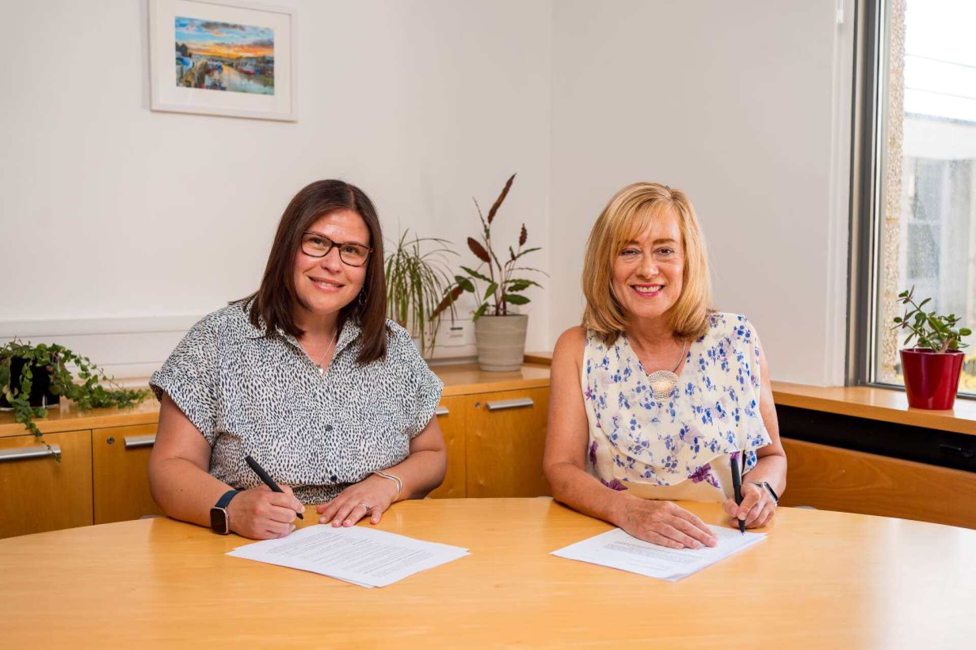 Georgina and Jane signing contracts and smiling